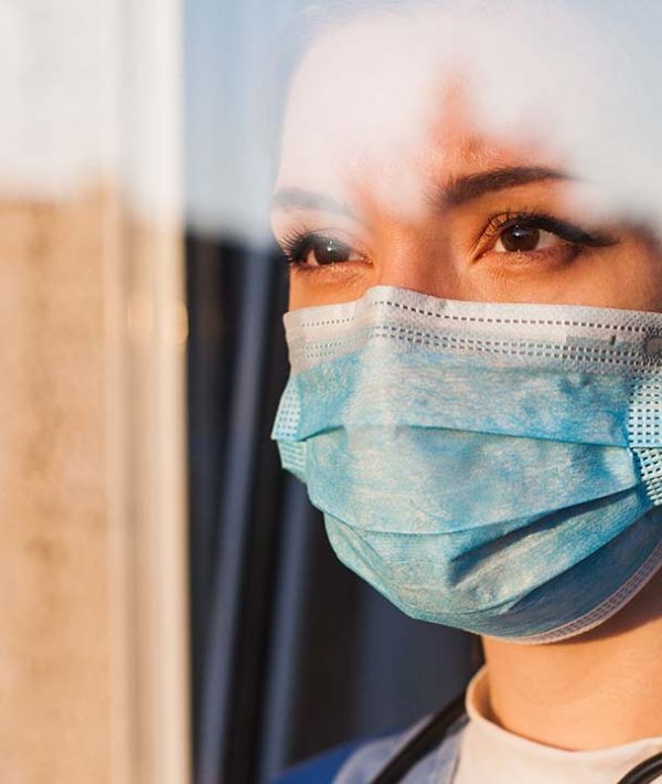 Young female UK NHS doctor looking through ICU window.jpg